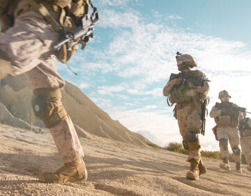 Squad Of Fully Equipped And Armed Soldiers Moving In Single File In The Desert