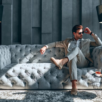 High-Net-Worth Man Sitting On A Classy Couch With A Cocktail