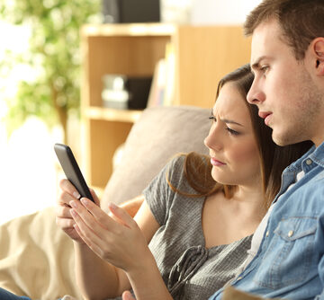Upset Couple Checking Mortgage Rates On A Phone