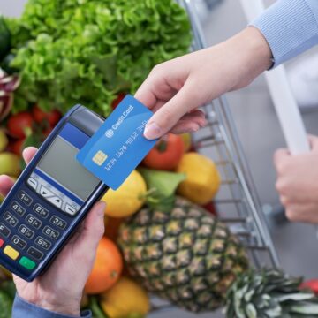 Woman Paying For Groceries Using Her Credit Card In A Card Reader In The Supermarket