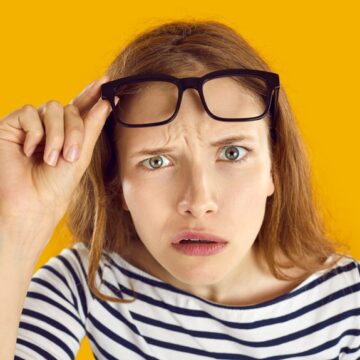 Bewildered Woman Lifts Her Eyeglasses For A Clearer View