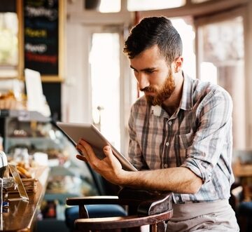 Small Business Barista Checking Tablet For Inventory And Revenue Information