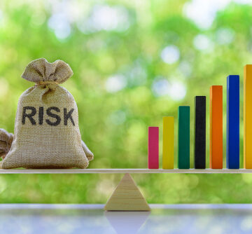 Risk Management Concept With A Bag Labeled Risk Balanced With A Rising Bar Graph