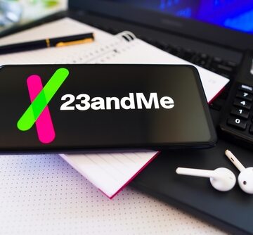 Photo Montage Of 23 And Me Logo On Tablet With Ear Buds And Calculator