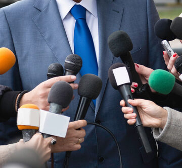 Many Journalists Holding Microphones And Interviewing VIP