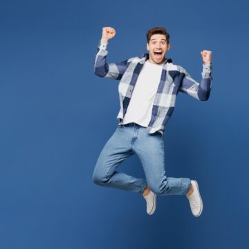 Happy Young Man In Plaid Shirt Jumping For Joy