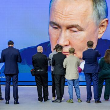 Extra Large Screen Of Vladimir Putin's Face In Front Of Row Of Journalists