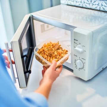 Person Heating Food In A Microwave Oven