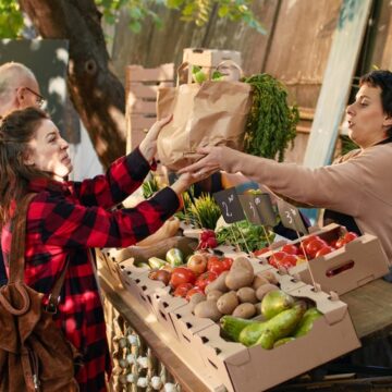 Woman And Man Purchasing Vegetables At Produce Stand