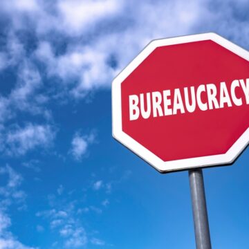 Traffic,Sign,With,Text,Bureaucracy,To,Stop,Unnecessary,Laws,And Traffic Stop Sign With Text Bureaucracy Against Blue Sky