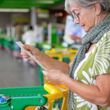 Senior Woman In The Supermarket Checks Her Grocery Receipt