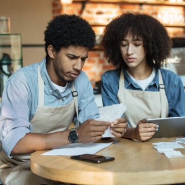 Concerned Small Business Owners Reviewing Bills And Receipts