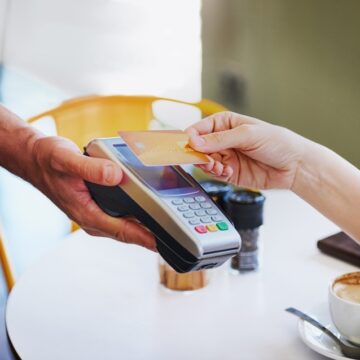 Person Handing Credit Card To Waitress At Coffee Shop