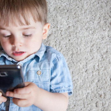 Sad Image Of Very Young Boy Playing With A Cellphone