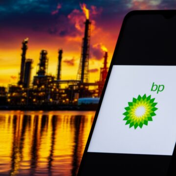 BP Logo Displayed On A Smartphone Screen With A Oil Refinery In The Background