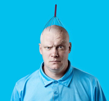 Bald, Bemused Man Scratching His Head With A Scalp Scratcher