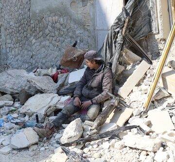 A Despondent Person Sits Atop A Pile Of Rubble From An Israeli Airstrike