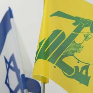 The Israel And Hezbollah Flags Unfurling Next To Each Other
