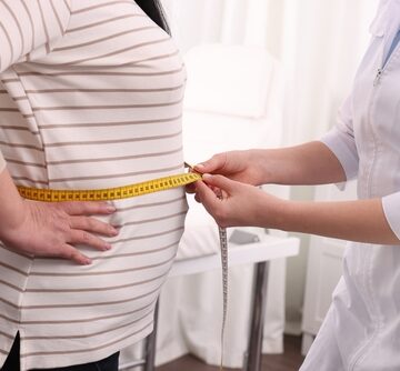 Nutritionist Measuring Overweight Woman's Waist With Tape Measure