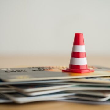 Close Up Of Red And White Traffic Cones Atop A Pile Of Credit Cards