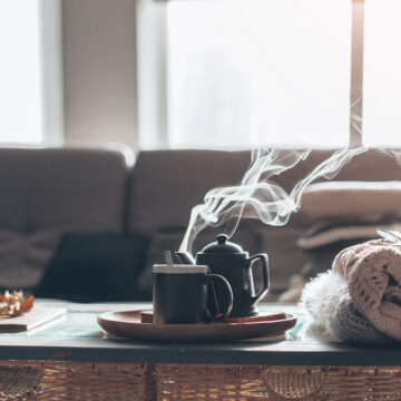 A Steaming Pot Of Tea And teacup Sitting On A Table In A Living Room