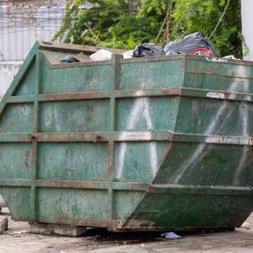 A Large Green Dumpster Full Of Trash