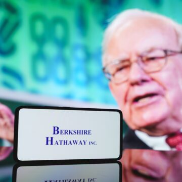 Berkshire,Hathaway,Company,And,Warren,Buffett,In,Background.,December,5, Berkshire Hathaway Company Logo On Mobile Phone With Chairman Warren Buffett In The Background