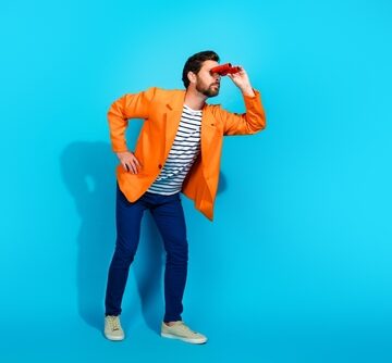 Man In Stylish Clothing Poses Playfully With Red Binoculars