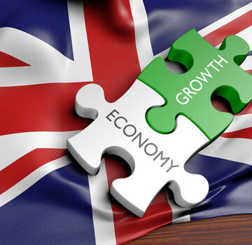 Puzzle Pieces With The Words "Economy" And "Growth" On Top Of The UK Flag