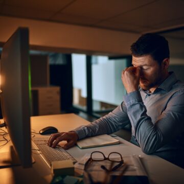 Stress,,Night,And,Business,Man,At,Desk,By,Computer,For TECHNOCRACY BRIEFS: HUMANS WORKING OVERTIME TO CREATE THEIR AI AGENT REPLACEMENTS