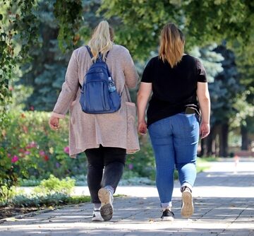 Two Overweight Women Walking In A Park