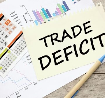 "Trade Deficit" Written On A Sheet Of Paper Atop Financial Charts And Calendar