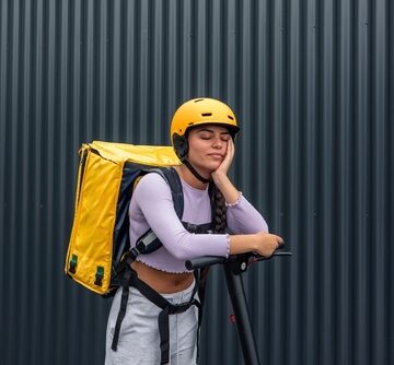 Sleepy Food Delivery Person Wearing A Yellow Backpack And Helmet, With Scooter