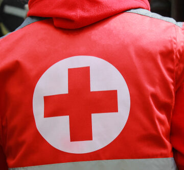 Medical Staff In Uniform With Red Cross On Back Of Jacket