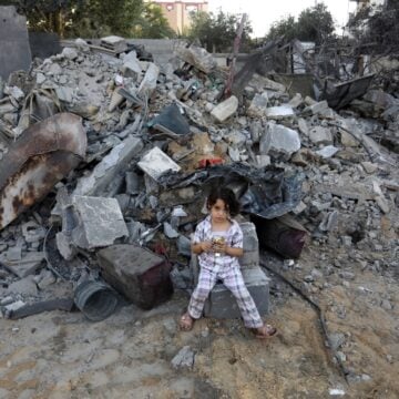 A Lone Palestinian Child Stands In Front Of The Rubble Of Homes Destroyed By Israeli Air Strikes