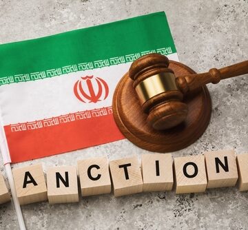 An Iranian Flag, A Judge's Gavel, And Wooden Cubes Spelling The Word Sanctions