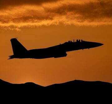 Fighter Jet At Sunset Flying Above Mountains