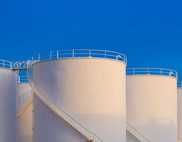 Crude Oil Storage Fuel Tanks Against A Bright Blue Sky