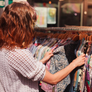 A Young Woman Browsing Through Clothing At A Thrift Market