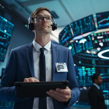 Young Trader/Broker On The Floor Of The Stock Exchange Using A Tablet