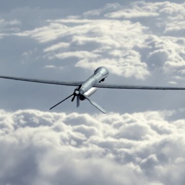 Unmanned Military Drone Flying In The Sky Above The Clouds