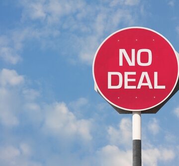 A Round Red Sign Against A Blue Sky That Reads "No Deal"