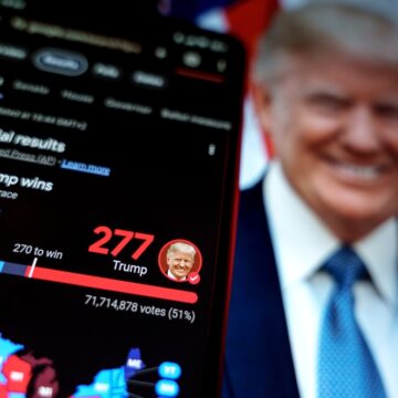 Closeup Of Mobile Phone With Donald Trump Election Win And Trump In Background