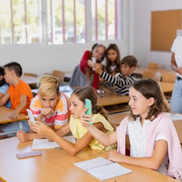 Schoolchildren,Use,Mobile,Phones,At,The,Lesson,In,The,Classroom School Children Use Mobile Phones During Classroom Lesson