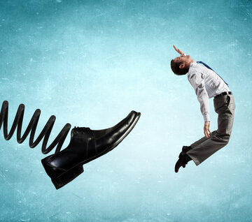A Businessman Getting Kicked By A Large Foot On A Spring "Getting The Boot"