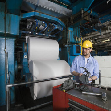 Young Factory Worker In A Hardhat Working In A Newspaper Printing Press
