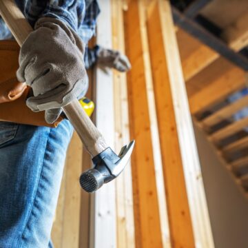A Construction Worker Grips A Hammer And Prepares To Work On A New Home