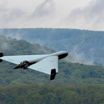 A Military, Kamikaze Drone Flying Low Over A Forest In The Clouds
