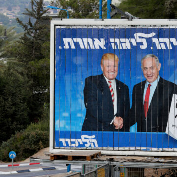 Israeli Citizens Walk Next To An Israeli Election Billboard Of Donald Trump And Bibi Netanyahu Shaking Hands
