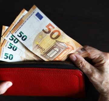 A Person's Hands Taking Euro Banknotes Out Of A Wallet